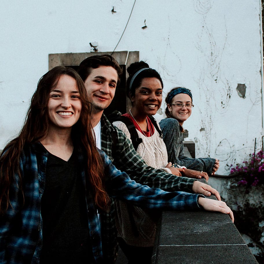 Four young people smile for the camera while standing on a bridge.