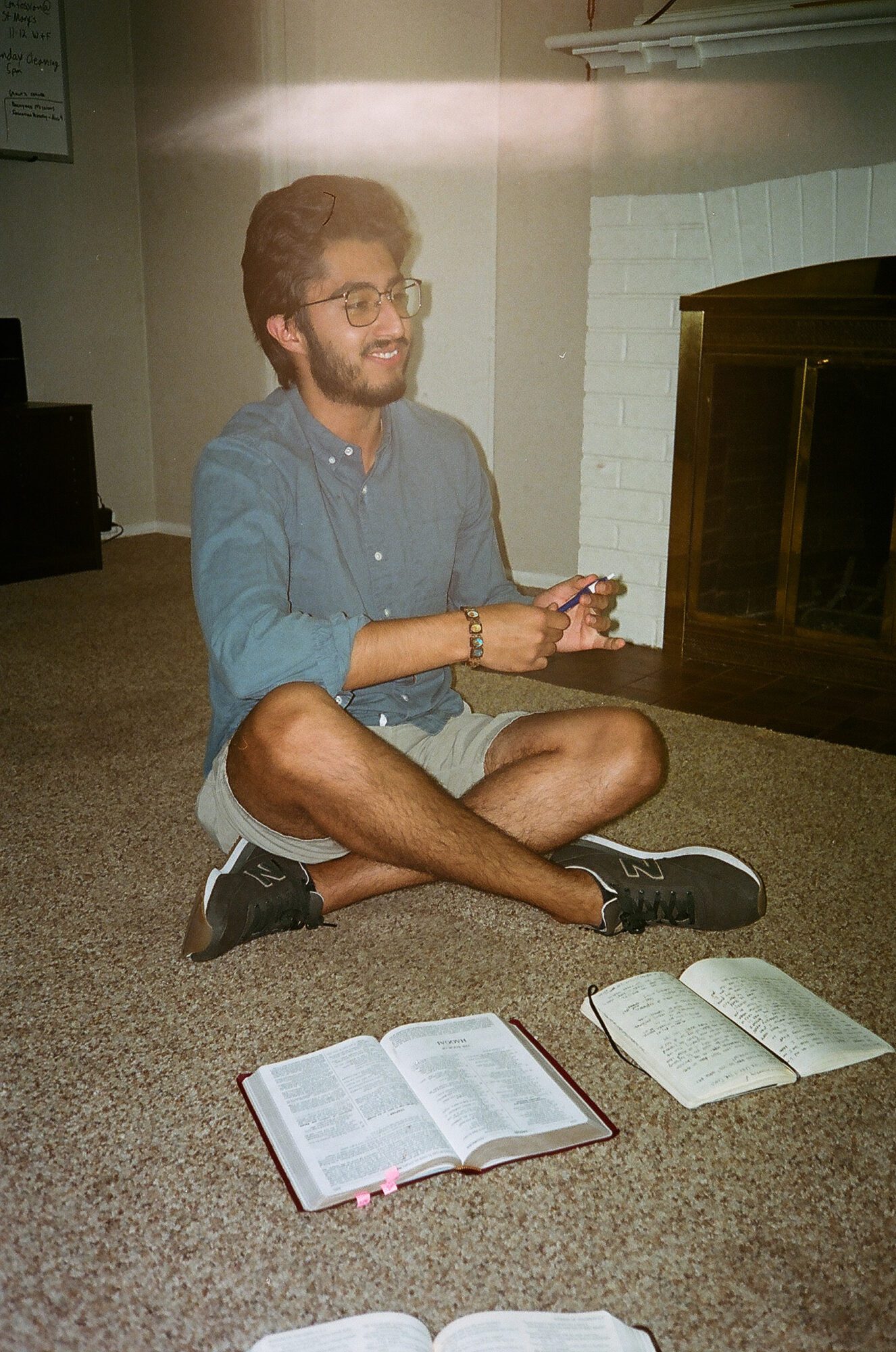 This image accompanies a blog post from FOCUS about Catholic evangelization. The image shows a young man sitting in the home of friends engaging in learning about Catholic evangelization.