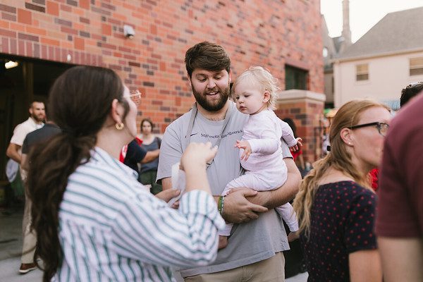 A man holds a baby while socializing at a FOCUS event. 