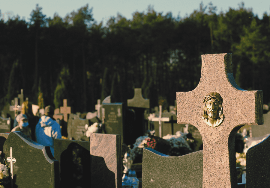 A graveyard with a cross tombstone and the image of Jesus. 