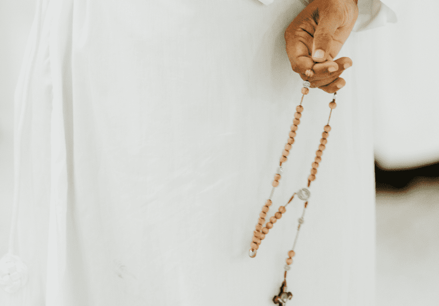 A priest holds a rosary behind his back. Catholic New Years Resolutions - pray more.