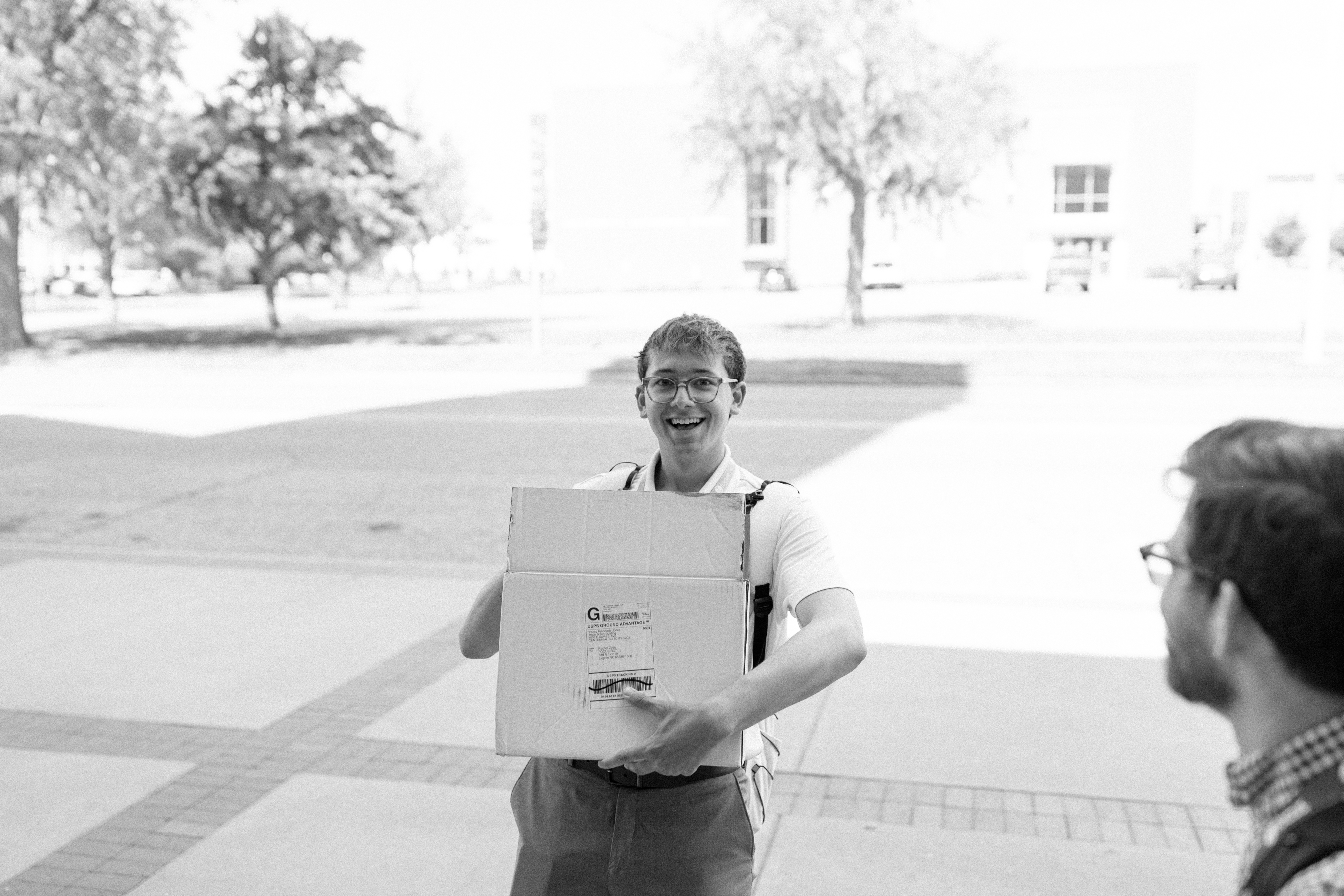 A young man holds a box smiling helping out at a local Catholic charity.