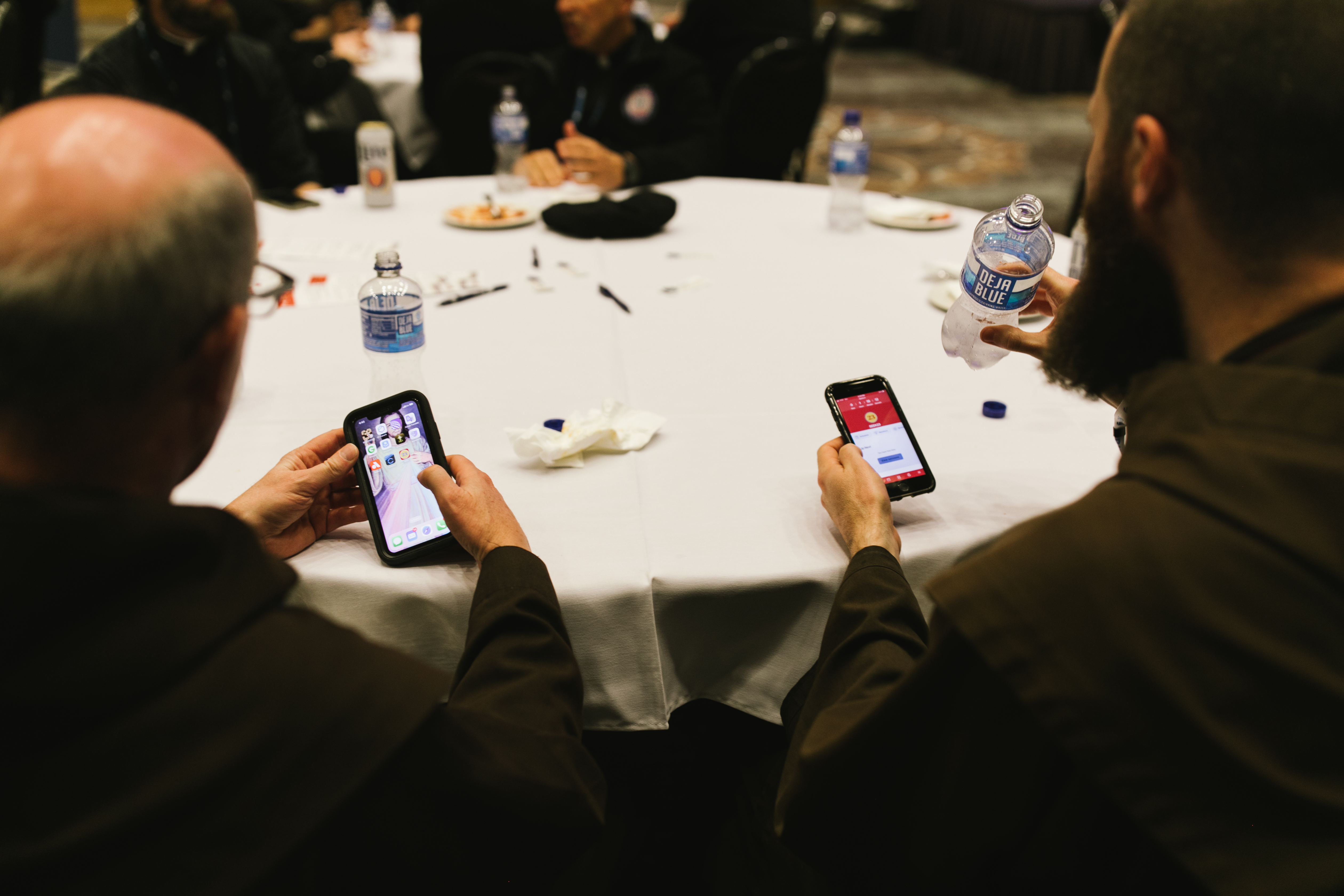 Two priests use their phones to pray at SEEK