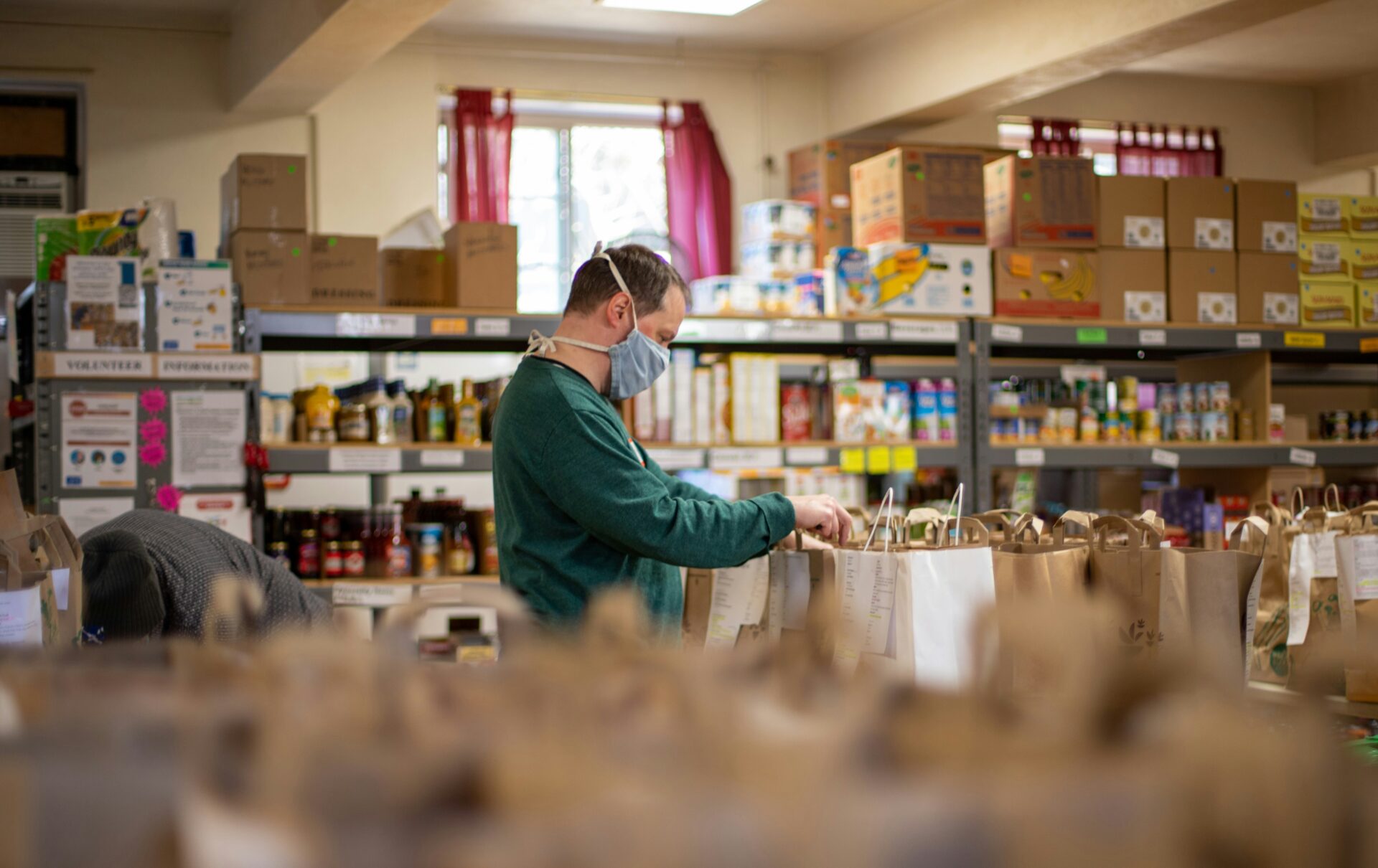 A man sorts groceries to volunteer at a Catholic charity. Catholic New Years Resolutions - volunteer.