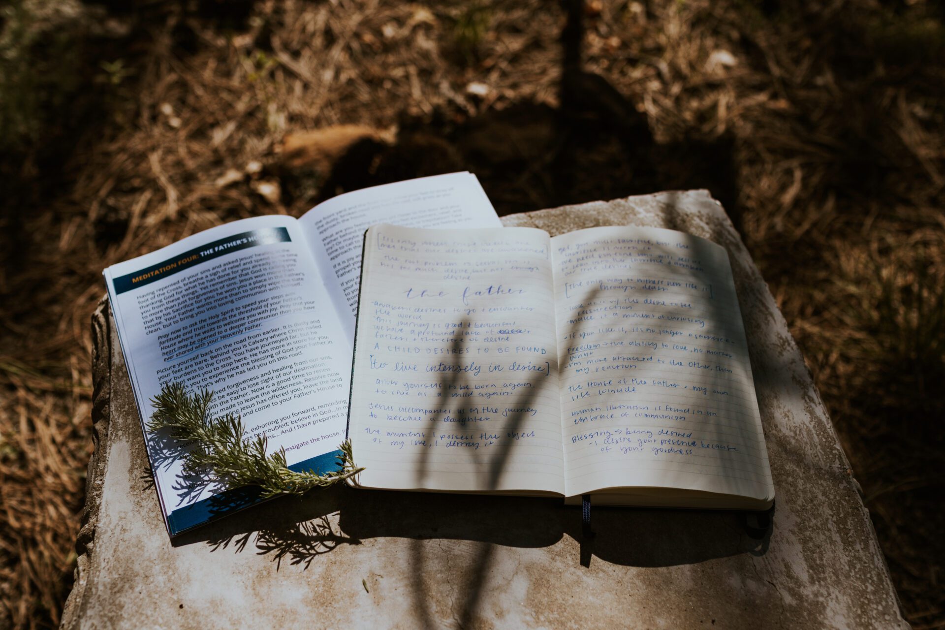 A bible and meditation guide book sit on a table with fall scenery around them. 