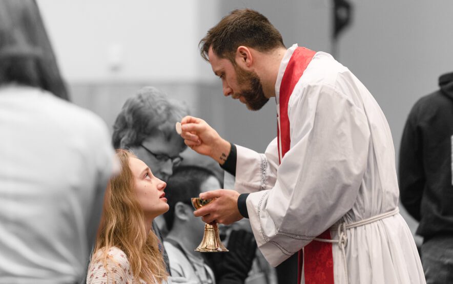 woman recieving the eucharist from a priest
