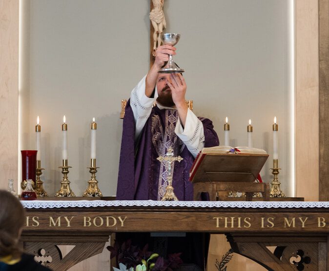 priest at the altar lifting up the eucharist